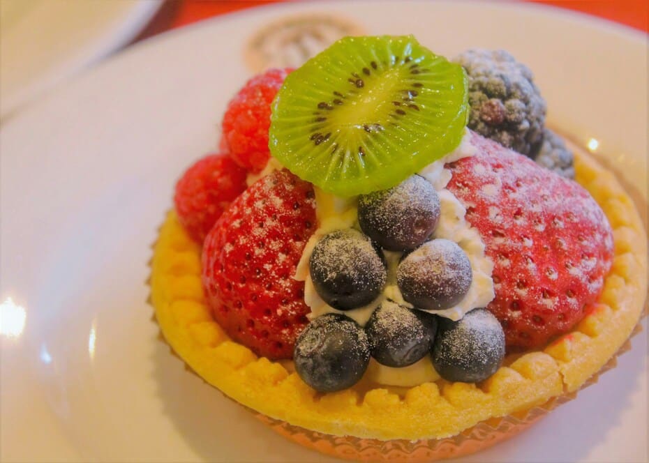 A vibrant vegan fruit tart topped with strawberries, blueberries, raspberries, blackberries, and a slice of kiwi — one of the best vegan desserts in the UK.