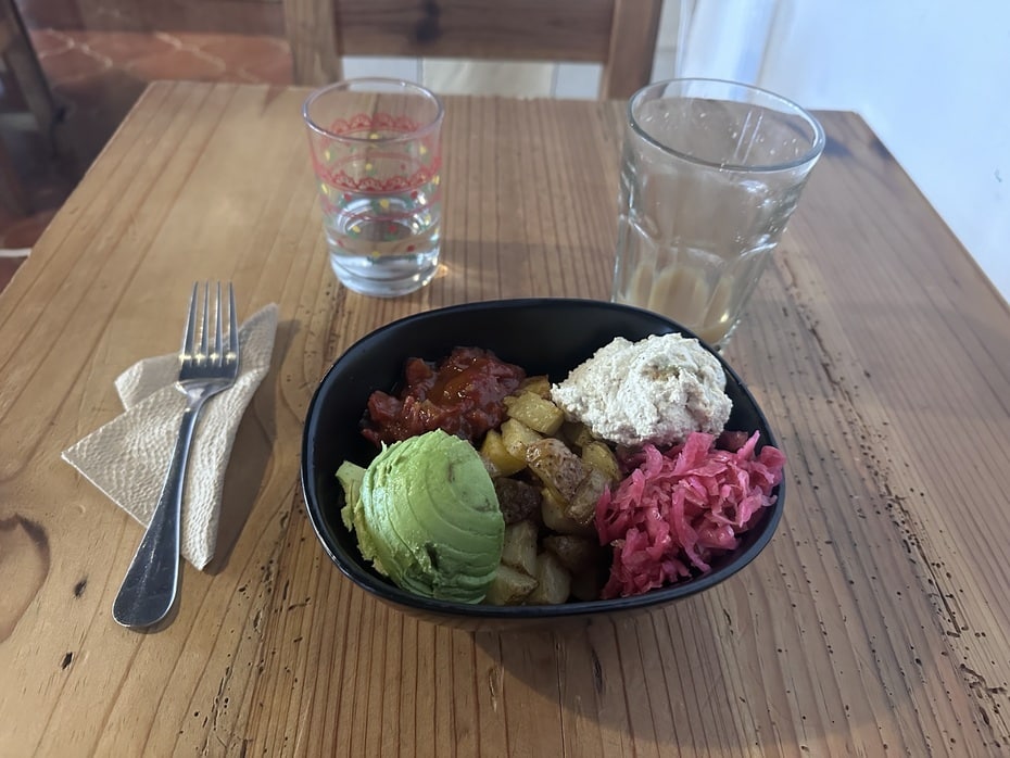 Vegan potato bowl in San Cristóbal de las Casas with avocado, cashew cheese, sauerkraut and salsa on a rustic wooden table