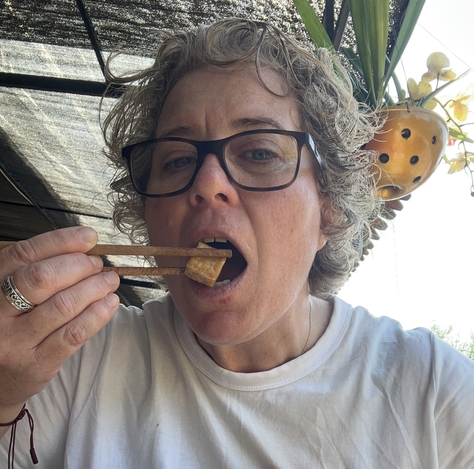 Siobhain from Vegan Verity eating tofu with chopsticks at an outdoor vegan cafe in Vietnam